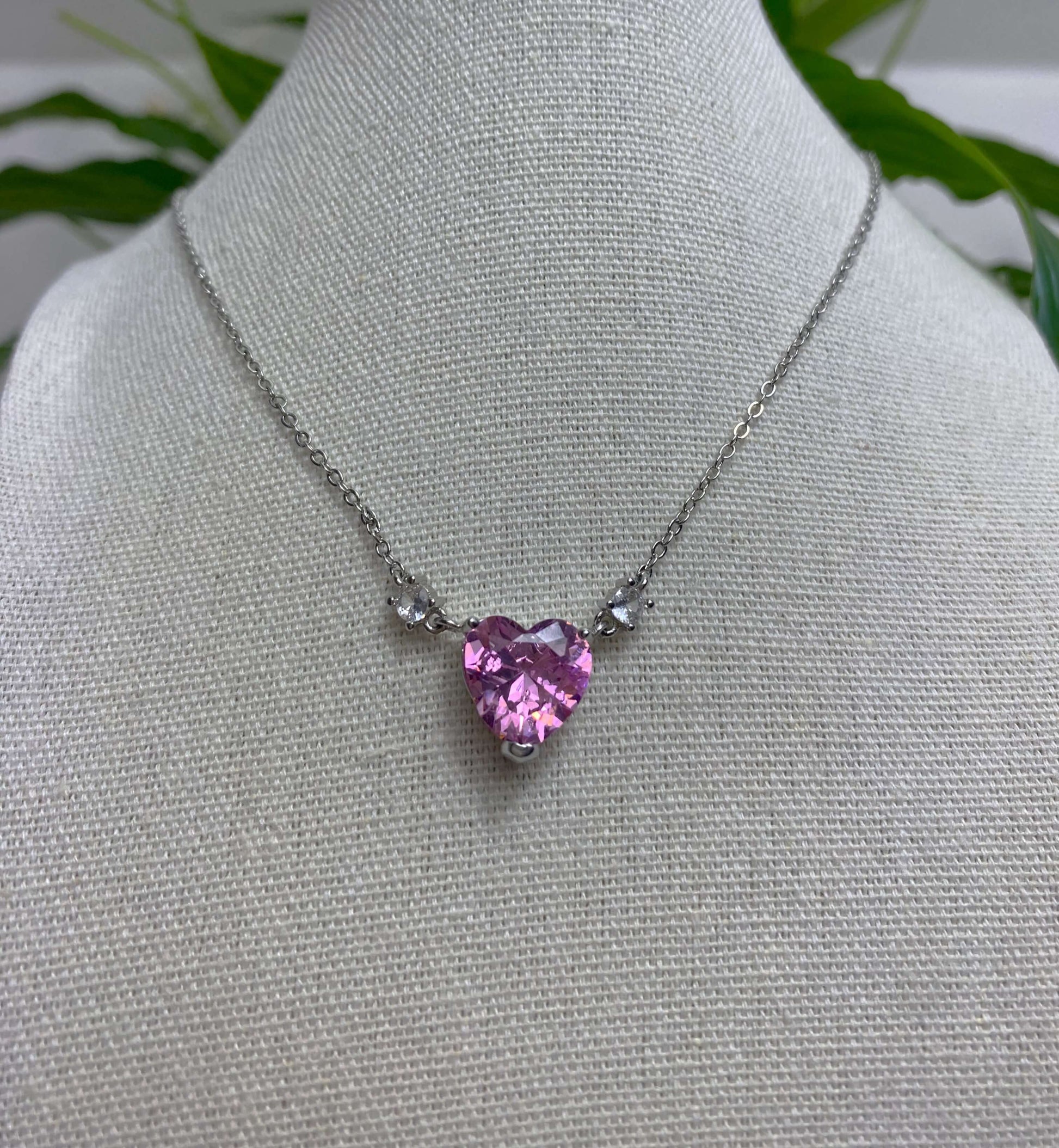 L'ode à l'amour.  Magnifique collier en acier inoxydable serti d'un cristal taillé en forme de cœur rose. Deux zircons entours ce cœur fort et gracieux.  Chaîne réglable de 46 à 60cm.  Résiste à l'eau.