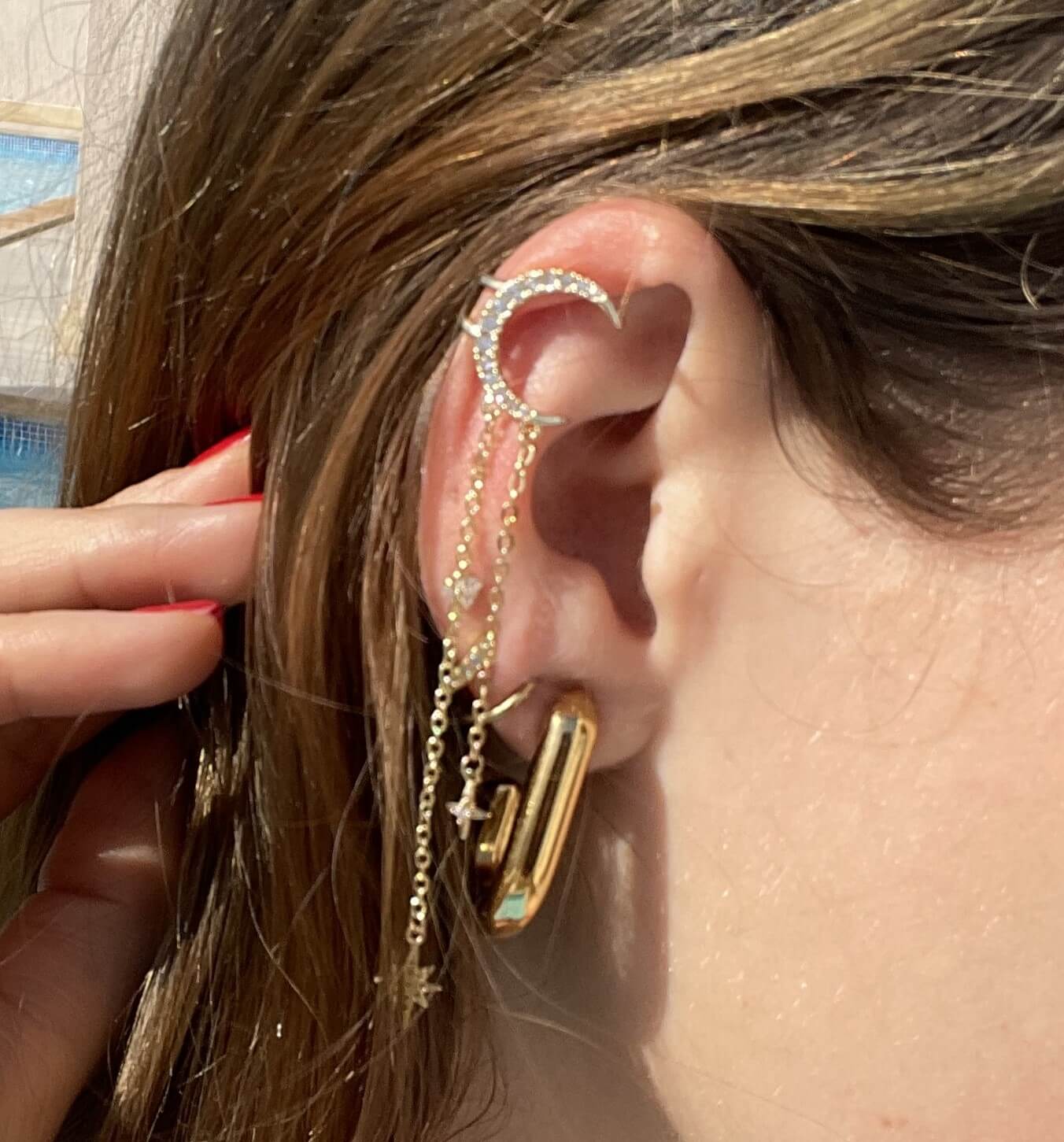 La beauté céleste à votre oreille avec l'Earcuff Star. Agrémenté d'une lune et des étoiles étincelantes en strass, ce faux piercing résistant à l'eau apporte éclat et sophistication. Le design ajustable s'adapte à votre oreille pour un look personnalisé. Ajoutez une touche de luxe à votre collection de bijoux.  Notre piercing s’accorde à merveille avec la bague et le collier « Star » de la même collection. 