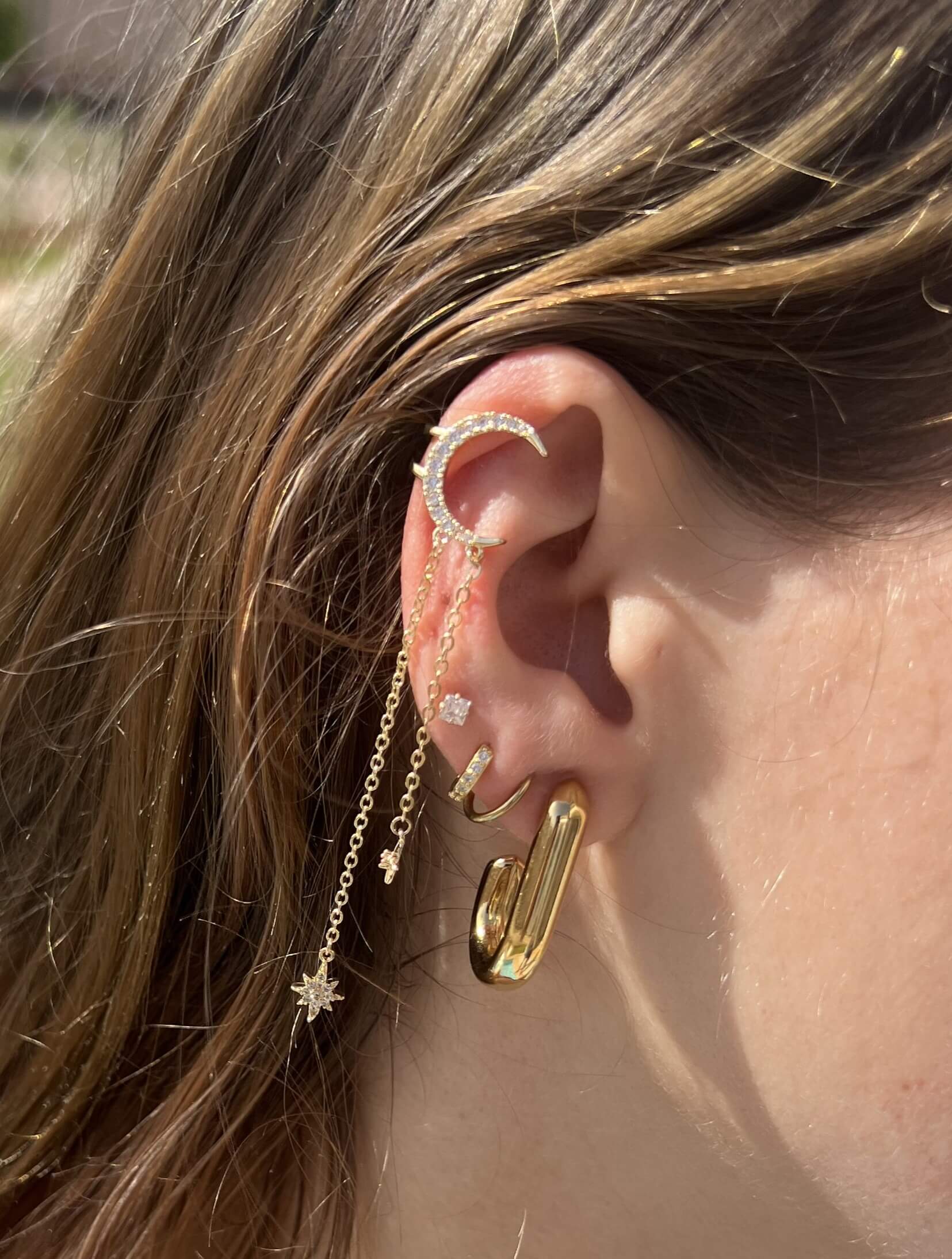 La beauté céleste à votre oreille avec l'Earcuff Star. Agrémenté d'une lune et des étoiles étincelantes en strass, ce faux piercing résistant à l'eau apporte éclat et sophistication. Le design ajustable s'adapte à votre oreille pour un look personnalisé. Ajoutez une touche de luxe à votre collection de bijoux.  Notre piercing s’accorde à merveille avec la bague et le collier « Star » de la même collection. 