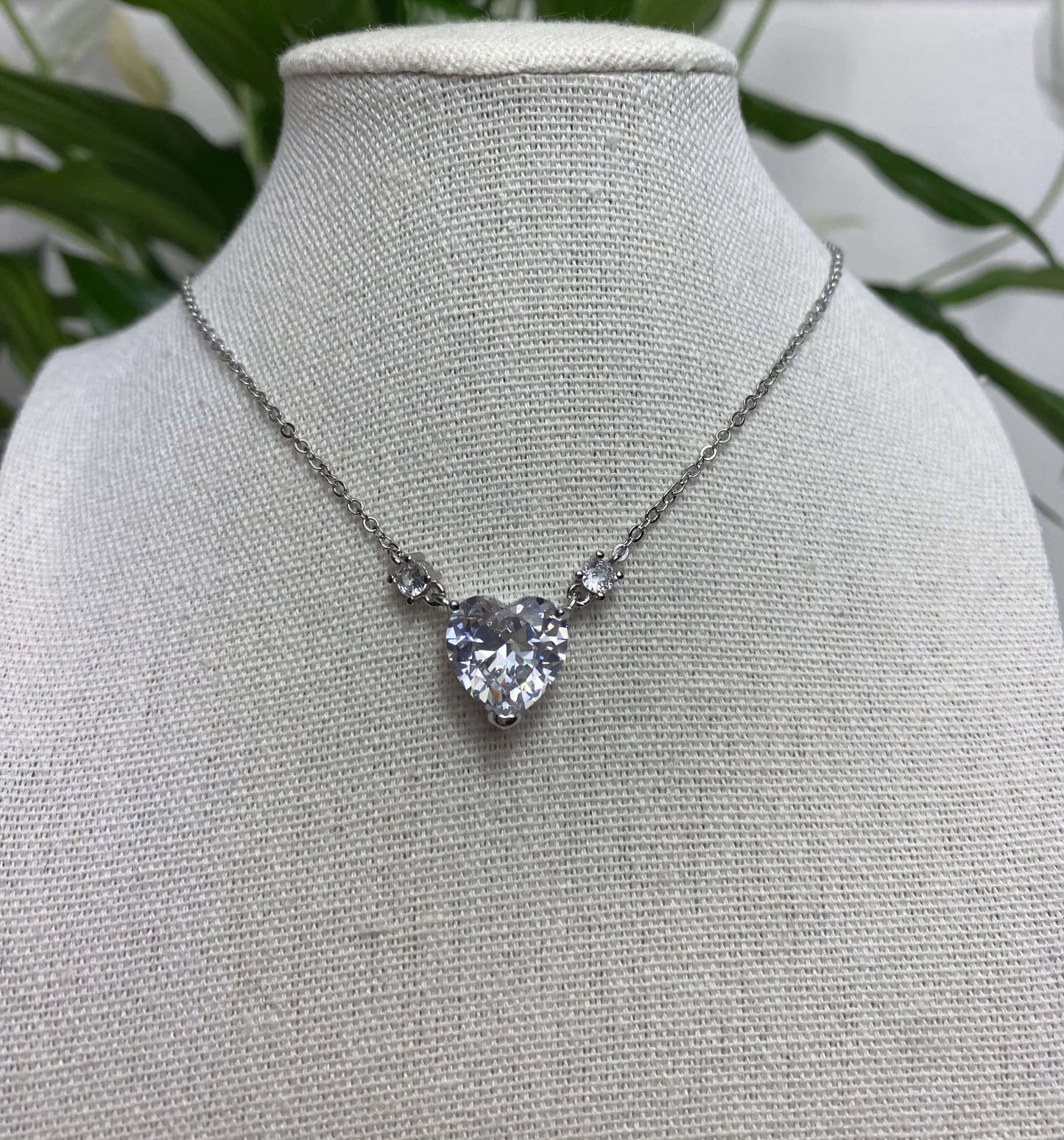 L'ode à l'amour.  Magnifique collier en acier inoxydable serti d'un cristal taillé en forme de cœur. Deux zircons entours ce cœur fort et gracieux.  Chaîne réglable de 46 à 60cm.  Résiste à l'eau.   